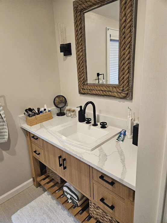 Natural wood vanity with white top and black fixtures